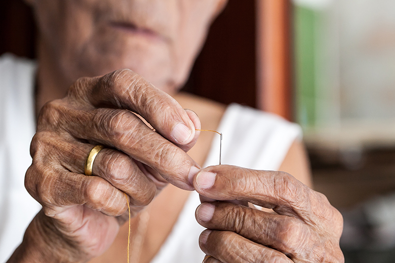 Old woman trying to thread a needle